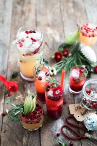 red drinks and cocktails on a wooden table with christmas decoration